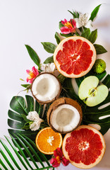 Summer tropical theme background or template with a space for a text, various fruits, green leaves and flowers. Bright summer background