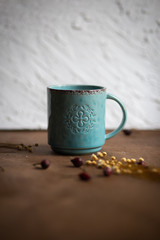 Blue cup on wooden tavle with old flowers