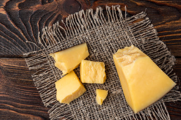 Parmesan cheese on dark wooden background.