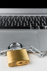 Padlock and chain with laptop computer on a white background. Cyber security abstract concept. Vertical orientation.