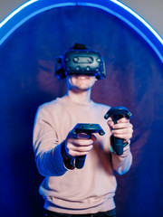 A young guy plays video games in a game room in a virtual reality helmet. gaming club.