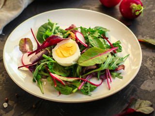 salad with radishes, boiled egg and mix lettuce leaves, appetizer, snack. food background. top view
