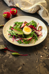 salad with radishes, boiled egg and mix lettuce leaves, appetizer, snack. food background. top view