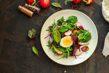 salad with radishes, boiled egg and mix lettuce leaves, appetizer, snack. food background. top view
