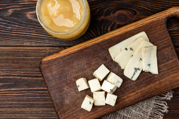 Cheese with mold on dark wooden background.