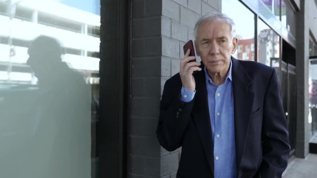 Elderly man on smartphone walks downtown, confused.