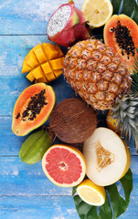 Fresh tropical Fruits on the beach with a palm leave. Assorted tropical fruits, orange,Ananas or pineapple and mango