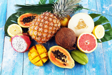 Fresh tropical Fruits on the beach with a palm leave. Assorted tropical fruits, orange,Ananas or pineapple and mango