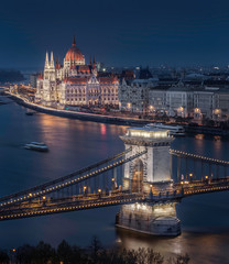 Fototapeta na wymiar Budapest, Hungary - Beautiful illuminated Szechenyi Chain Bridge with the Parliament of Hungary at blue hour with sightseeing boat on River Danube