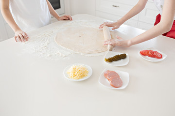 Obraz na płótnie Canvas Children's hands roll out the pizza dough on a white table. Having fun together in the kitchen. View from above.
