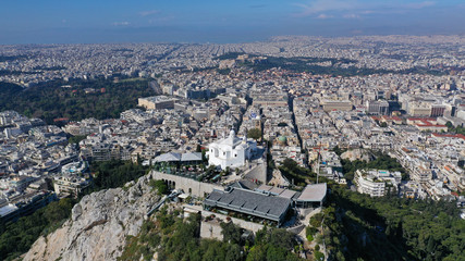 Aerial drone panoramic photo of iconic Saint George Lycabettus chapel as seen from top of hill, all Athens cityscape and Acropolis hill at the background, Athens historic centre, Attica, Greece