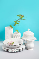 Mock up image with White tableware for serving and flower vases on grey table against blue...