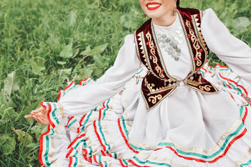 A woman in traditional embroidered Turkic Eastern clothes performs a national dance in the Park