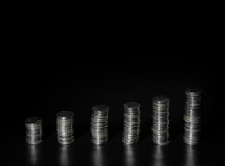 Silver coin stack isolated on dark background. Stacks of silver coins of various heights. Vertical bar chart.