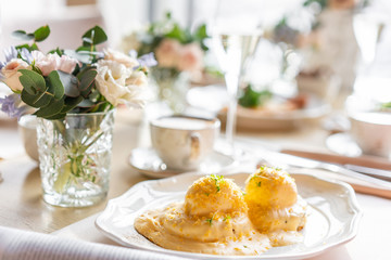 Egg Benedict on warm toast brioche. Two eggs delicious hollandaise sauce. Light morning Breakfast on table in restaurant.