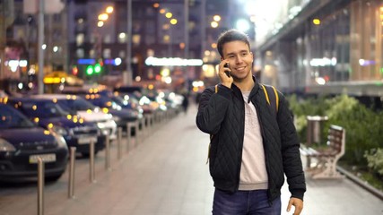 Young Attractive Man Speaking by Phone in the evening city street with bokeh light effect