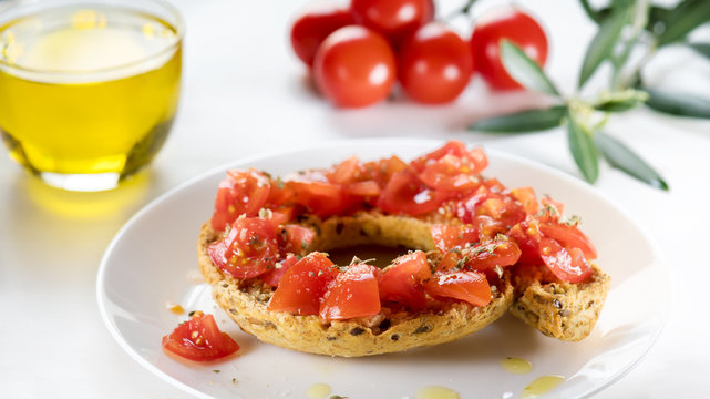 Tipical summer dish of Puglia - friselle. Classical frisella with tomato, oregano and olive oil. Dried bread called freselle. Healthy vegetarian food.