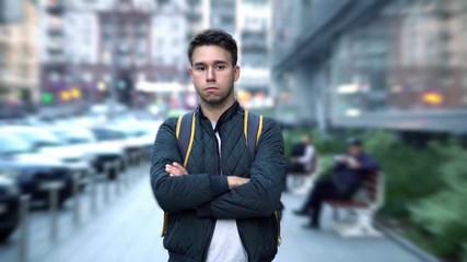 Timelapse of young serious man standing in the street with crowd of people.