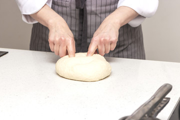 Baking concept. Hard working women prepares pastry by himself, kneads dough on wooden counter with flour and rolling pin. Women cook bakes bread or delicious bun or pasta