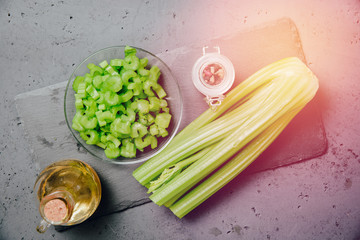 Cut and whole celery on a stone counter top. Top view of vegetables. Concept of eating vegetables, using vegetables for dishes. Dish for a vegetarian. Healthy nutrition, vitamins.