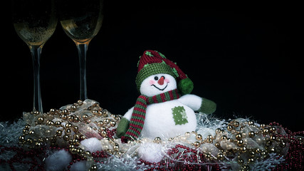fun toy snowman and two glasses of champagne on a black backgro