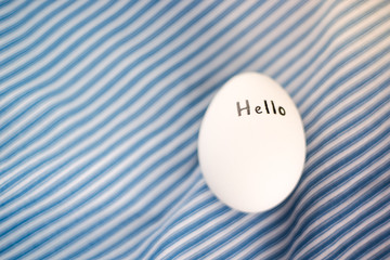 White chicken egg with black inscription hello