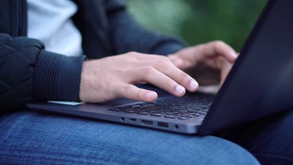 Close-up View of Man Using Laptop in the city street with bokeh effect