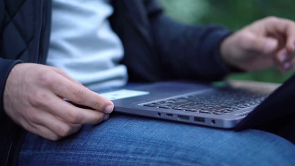 Close-up View of Man Using Laptop in the city street with bokeh effect