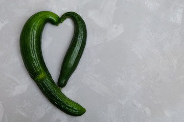 Trendy organic cucumbers shaped in a form of heart. Image with copy space, top view.