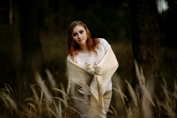 red-haired girl in bright clothes on a background of autumn forest and yellow ears on a sunny day