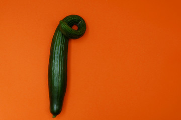 Organic ugly cucumber on orange background. Image with copy space, top view.