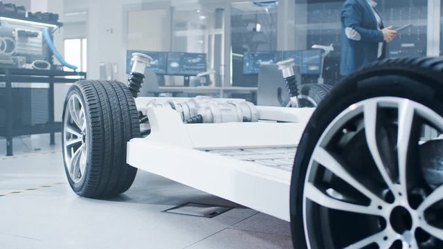 Concept of Authentic Electric Car Platform Chassis Prototype Standing in High Tech Industrial Machinery Design Laboratory. Hybrid Frame include Tires, Suspension, Engine and Battery. 