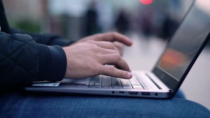 Close-up View of Man Using Laptop in the city street with bokeh effect