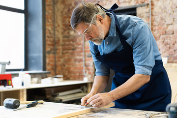 Mature handsome joiner work in carpentry. He is successful entrepreneur at his workplace.