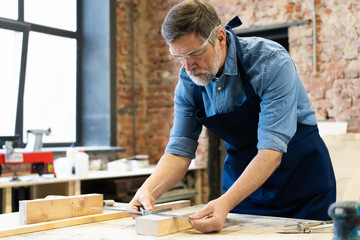 Mature handsome joiner work in carpentry. He is successful entrepreneur at his workplace.