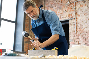 Mature handsome joiner work in carpentry. He is successful entrepreneur at his workplace.