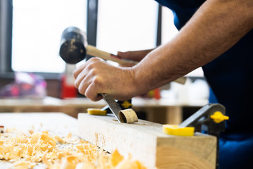 Carpenter working on woodworking machines in carpentry shop. A man works in a carpentry shop.