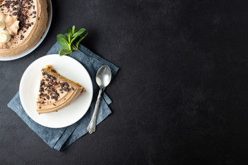 Tasty cake decorated with cream and dark chocolate on black background. Top view with copy space.