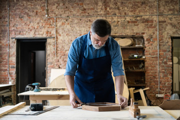 Mature handsome joiner work in carpentry. He is successful entrepreneur at his workplace.