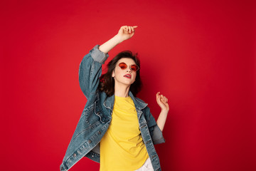 Pretty hipster girl posing isolated on red