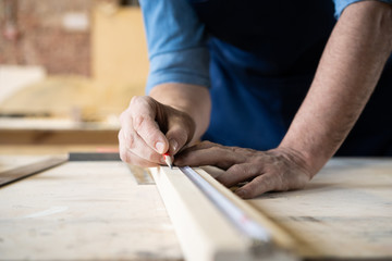 Fototapeta na wymiar Carpenter working on woodworking machines in carpentry shop. A man works in a carpentry shop.