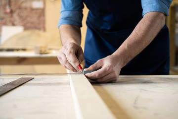 Fototapeta na wymiar Carpenter working on woodworking machines in carpentry shop. A man works in a carpentry shop.