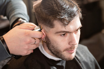 Barber work with clipper machine in barbershop. Professional trimmer tool cuts beard and hair on...