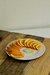 Sliced ​​orange and pear in plate on wooden background