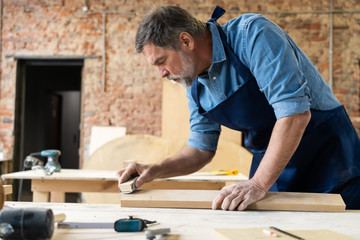 Mature handsome joiner work in carpentry. He is successful entrepreneur at his workplace.