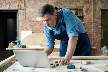 Mature handsome joiner work in carpentry. He is successful entrepreneur at his workplace.