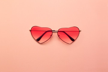 Bright coral heart-shaped glasses on a orange paper background.