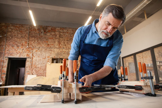 Mature handsome joiner work in carpentry. He is successful entrepreneur at his workplace.