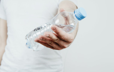 Drinking water from the bottle. The man gives a bottle of water in front of him. The concept of thirst, the desire to drink clean water. Taking care of health, proper hydration of the body.