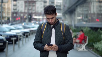 Young Attractive Man Typing Message Using Smartphone in the city street
